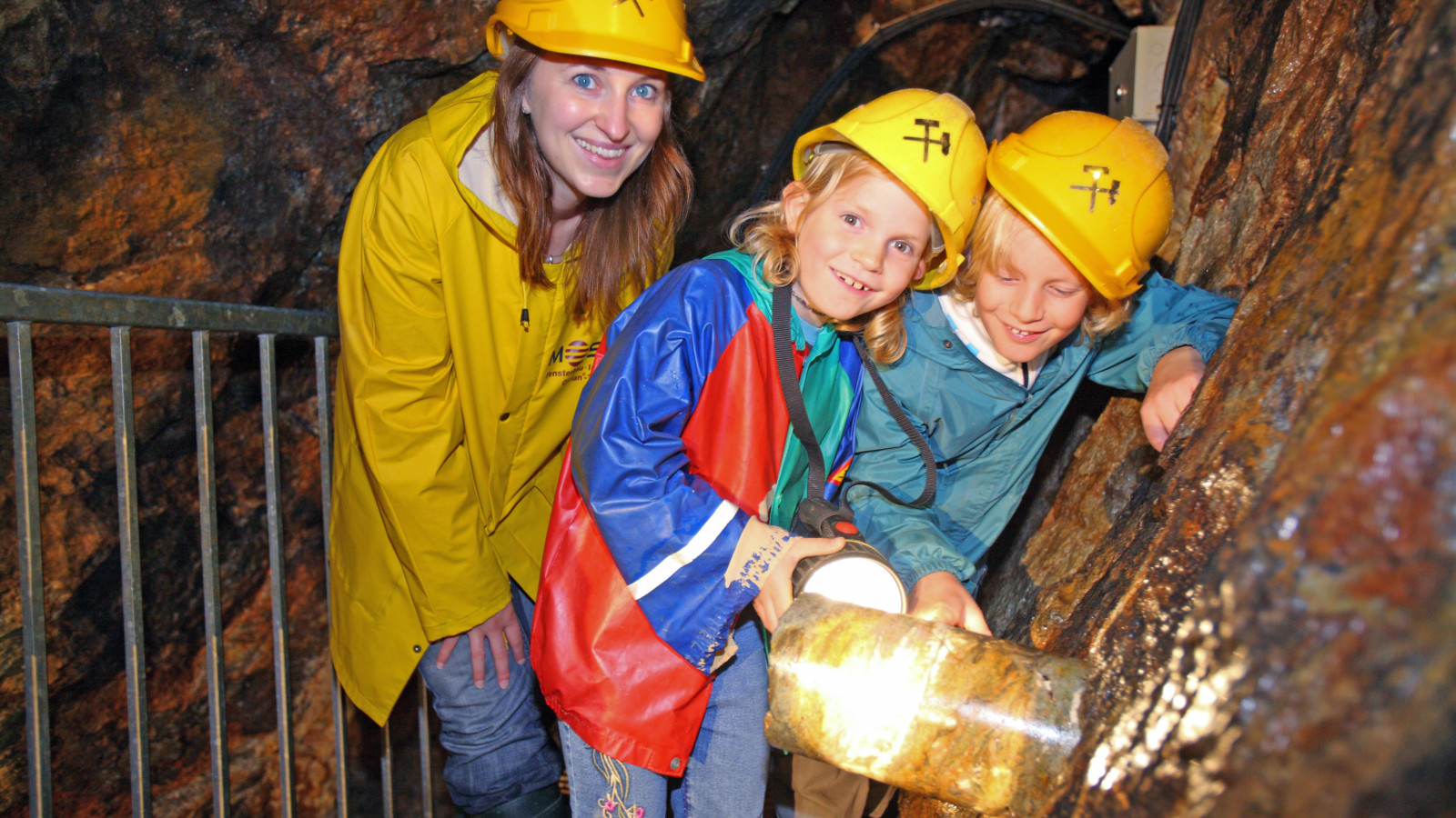 Kinder im Bergwerk bestaunen einen Bohrkern im Stollen.